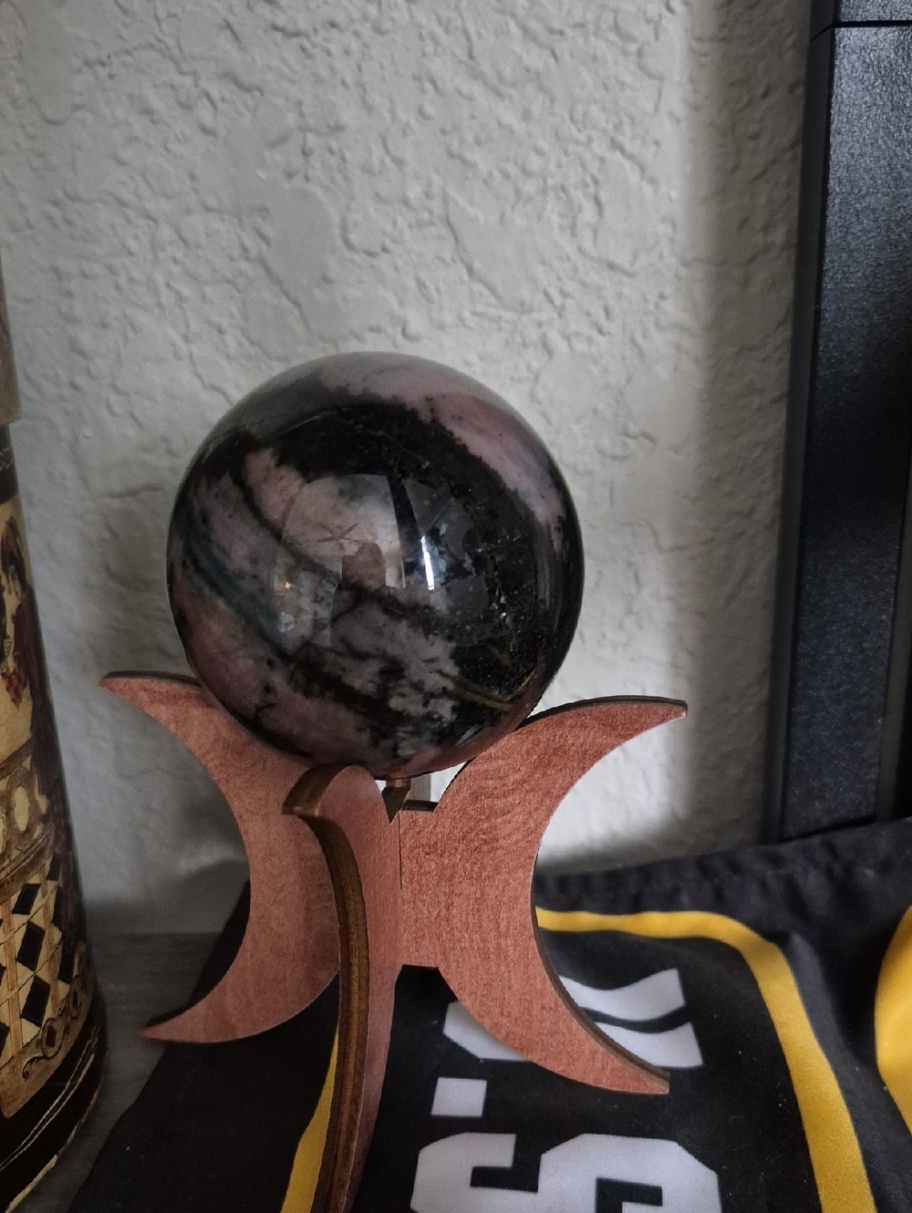 Polished Pink and Black Crystal Sphere on Wooden Stand